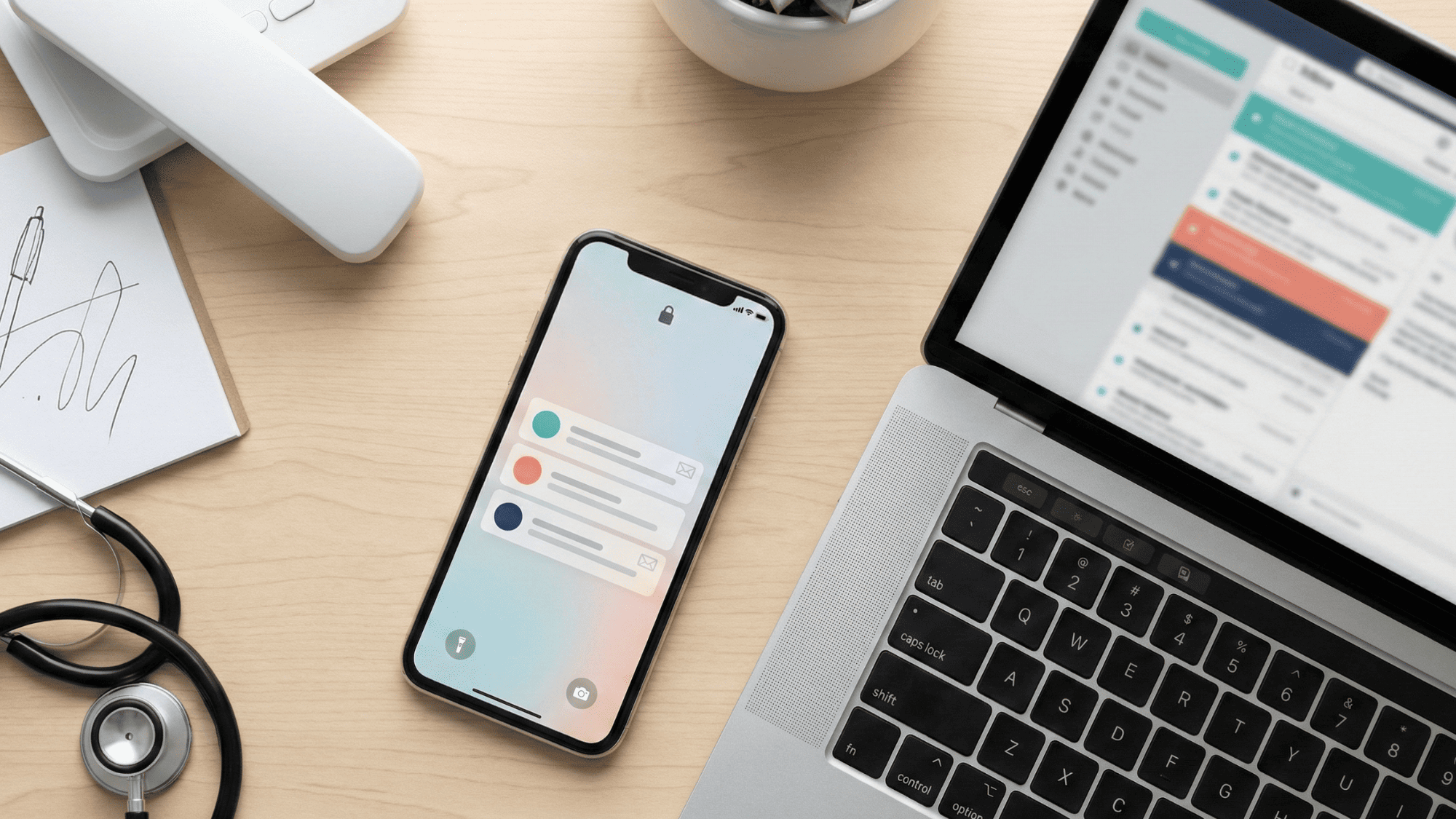 Flat lay of medical office desk with smartphone laptop and desk phone showing multi-channel patient communication