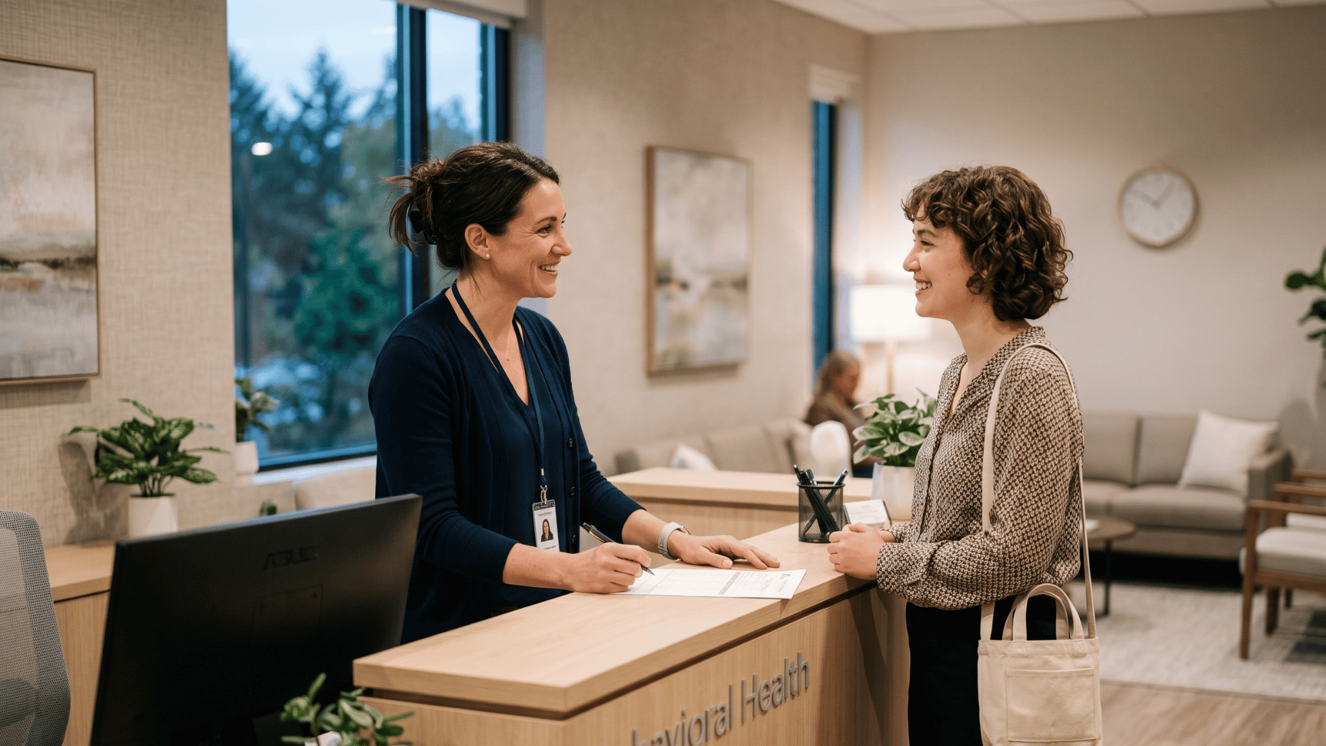 Intake coordinator greeting a returning client at a behavioral health practice reception