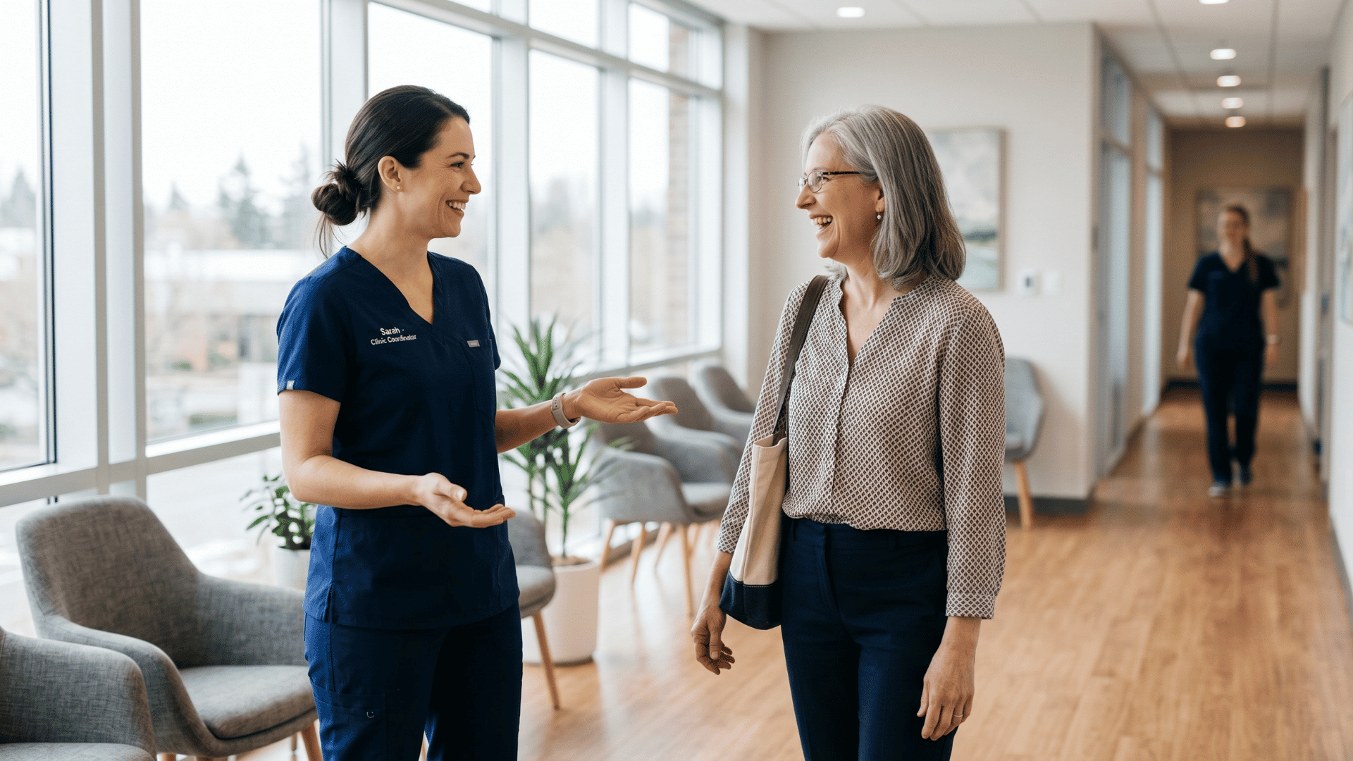 Clinic team member warmly greeting a patient at check-in in a bright medical office