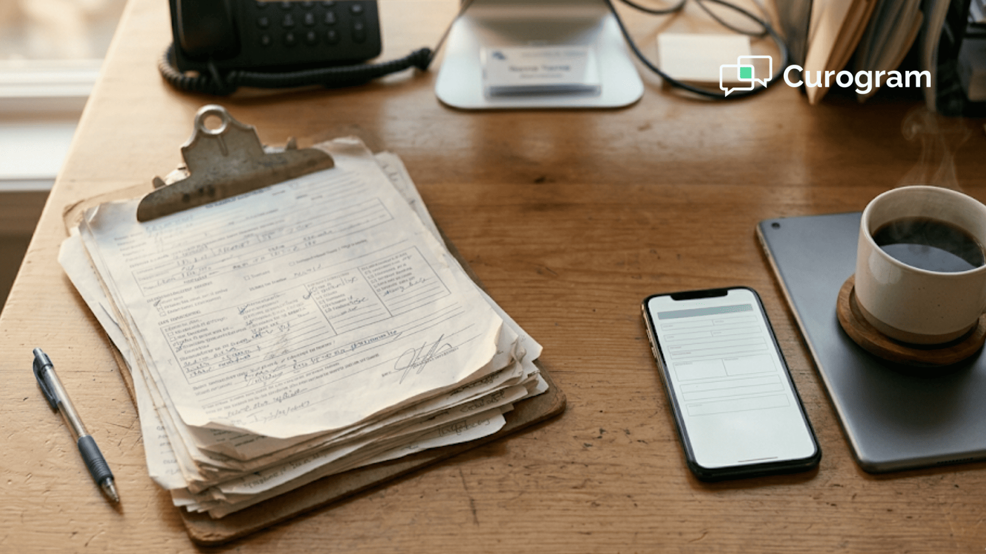 Cluttered clipboard of handwritten patient forms next to a modern smartphone and tablet
