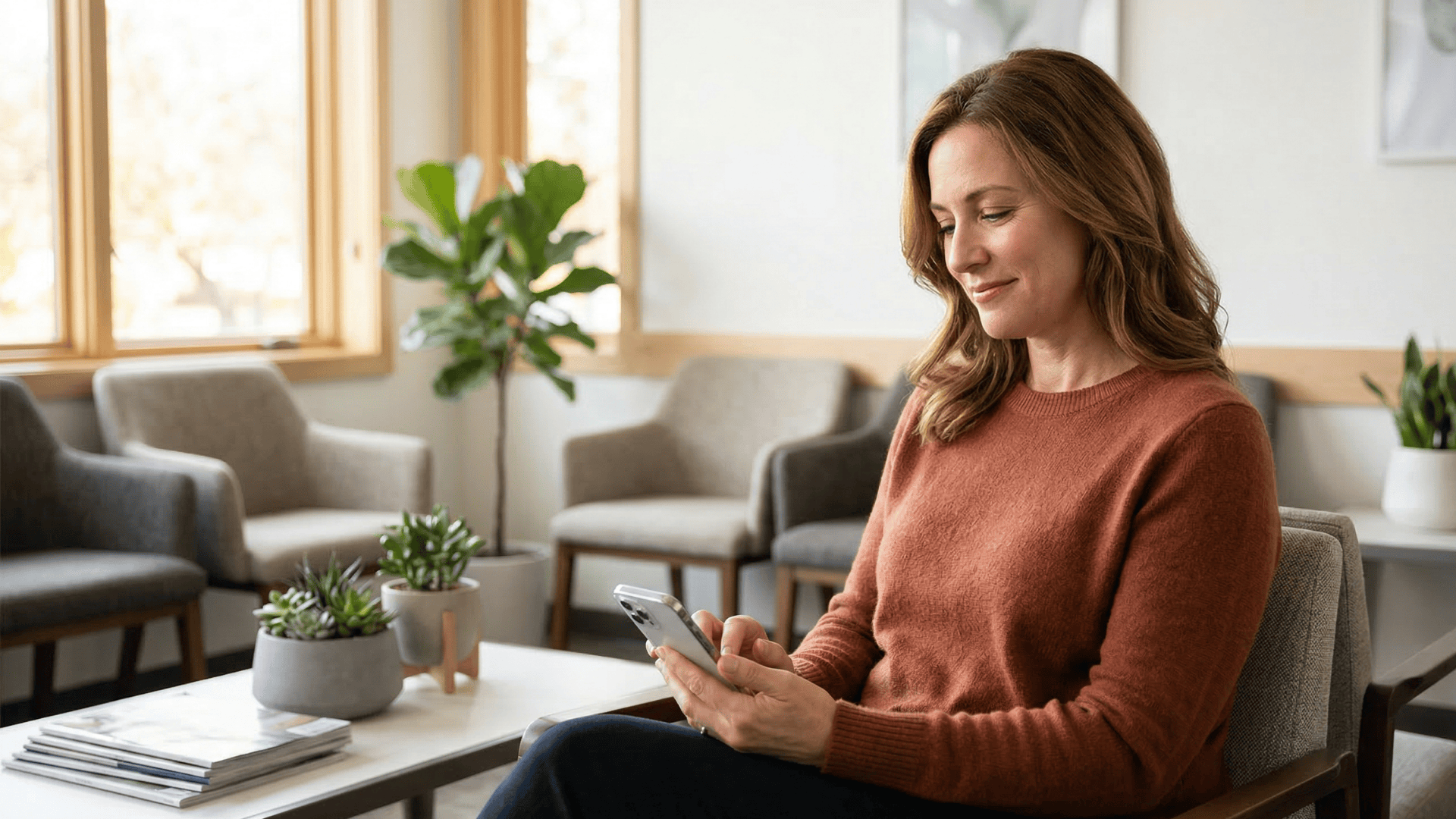 Patient replying to appointment confirmation text in a calm medical office waiting room.