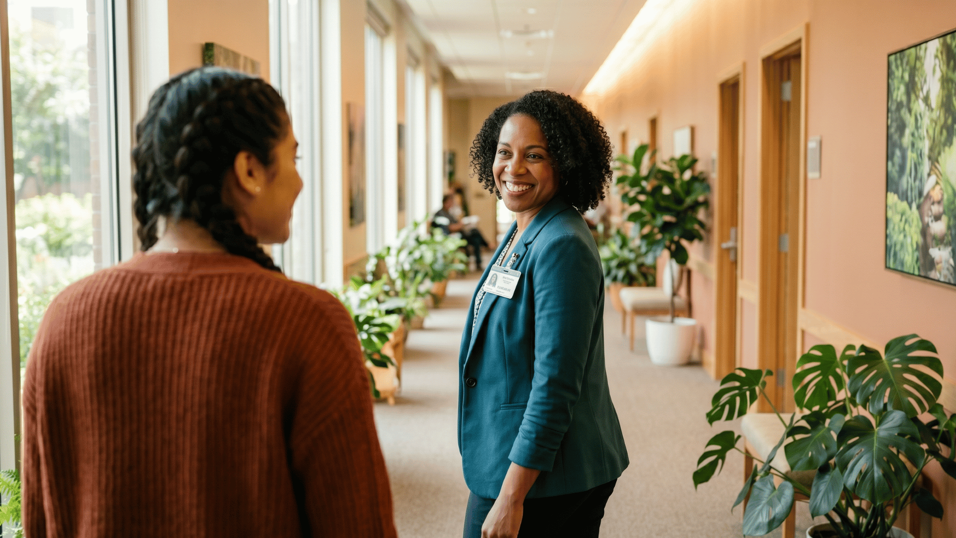 Behavioral health clinician walking with a new client through a bright practice hallway