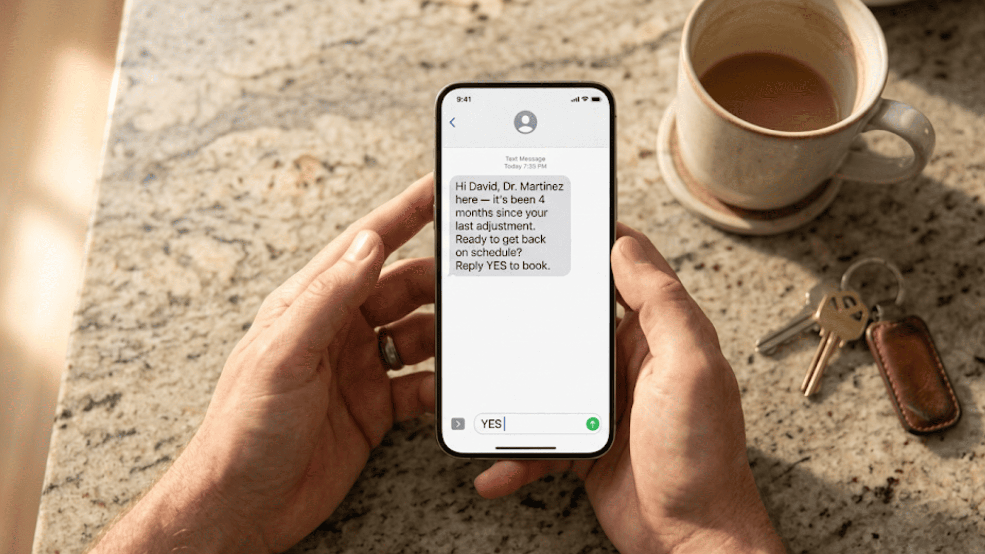 Close-up of a patient's phone showing a personalized recall text from their doctor with a YES reply