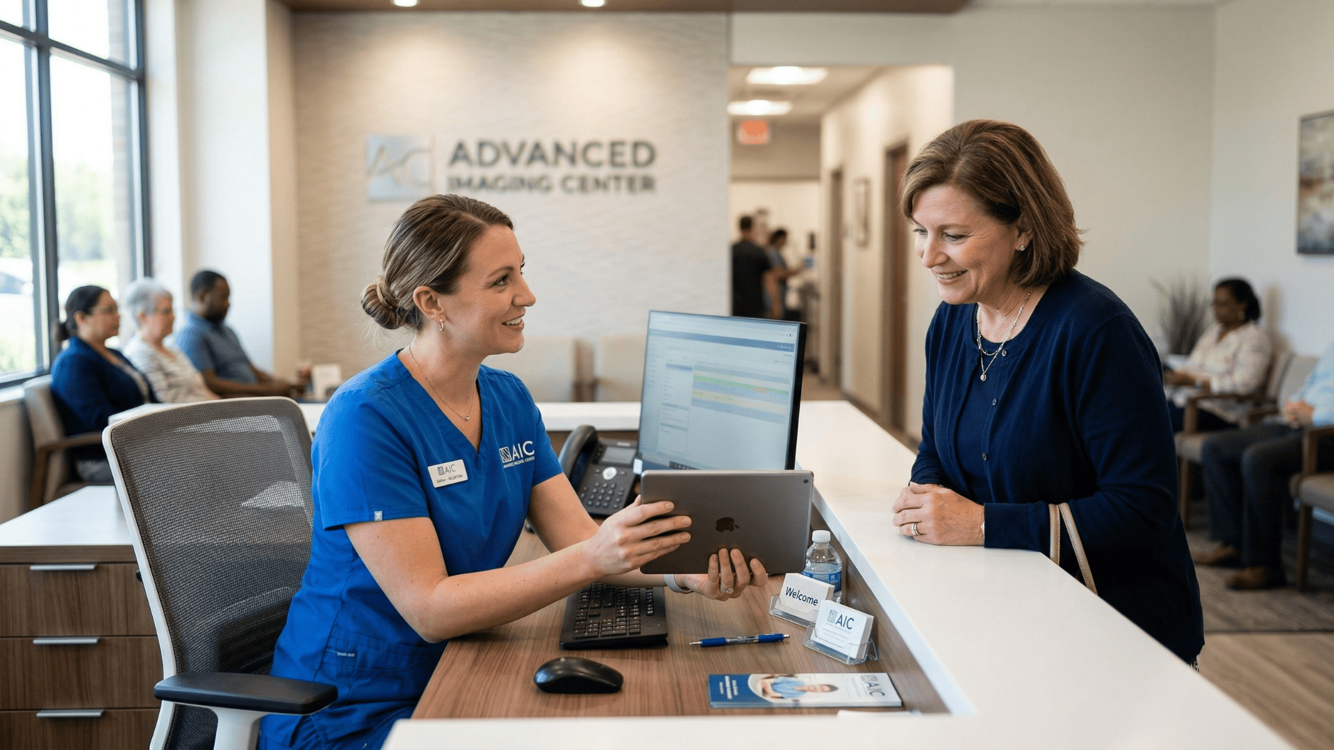 Front desk staff showing a patient a text-based imaging follow-up reminder on a tablet