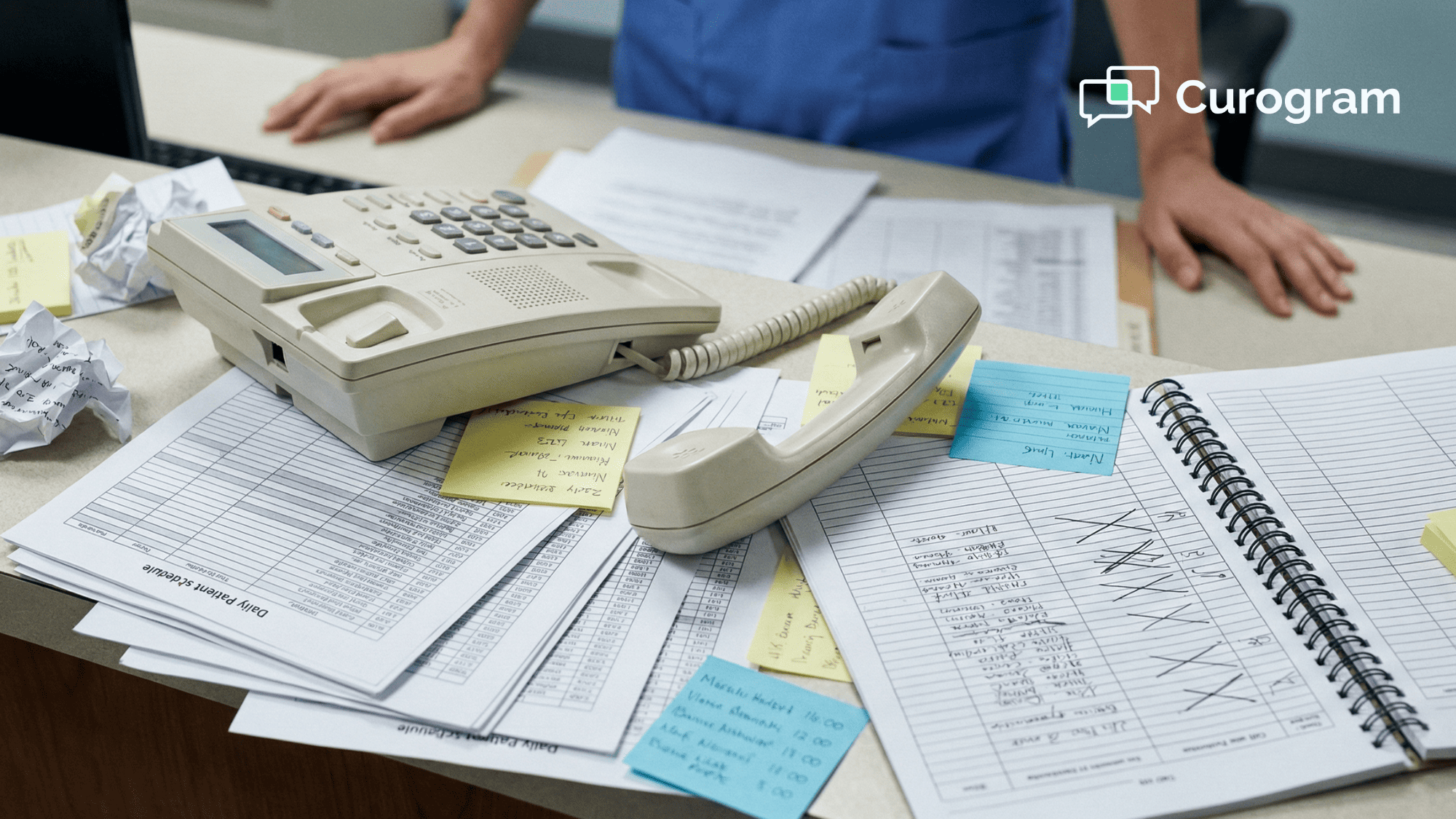 Overhead view of a medical office desk with a phone off the hook surrounded by printed patient schedules