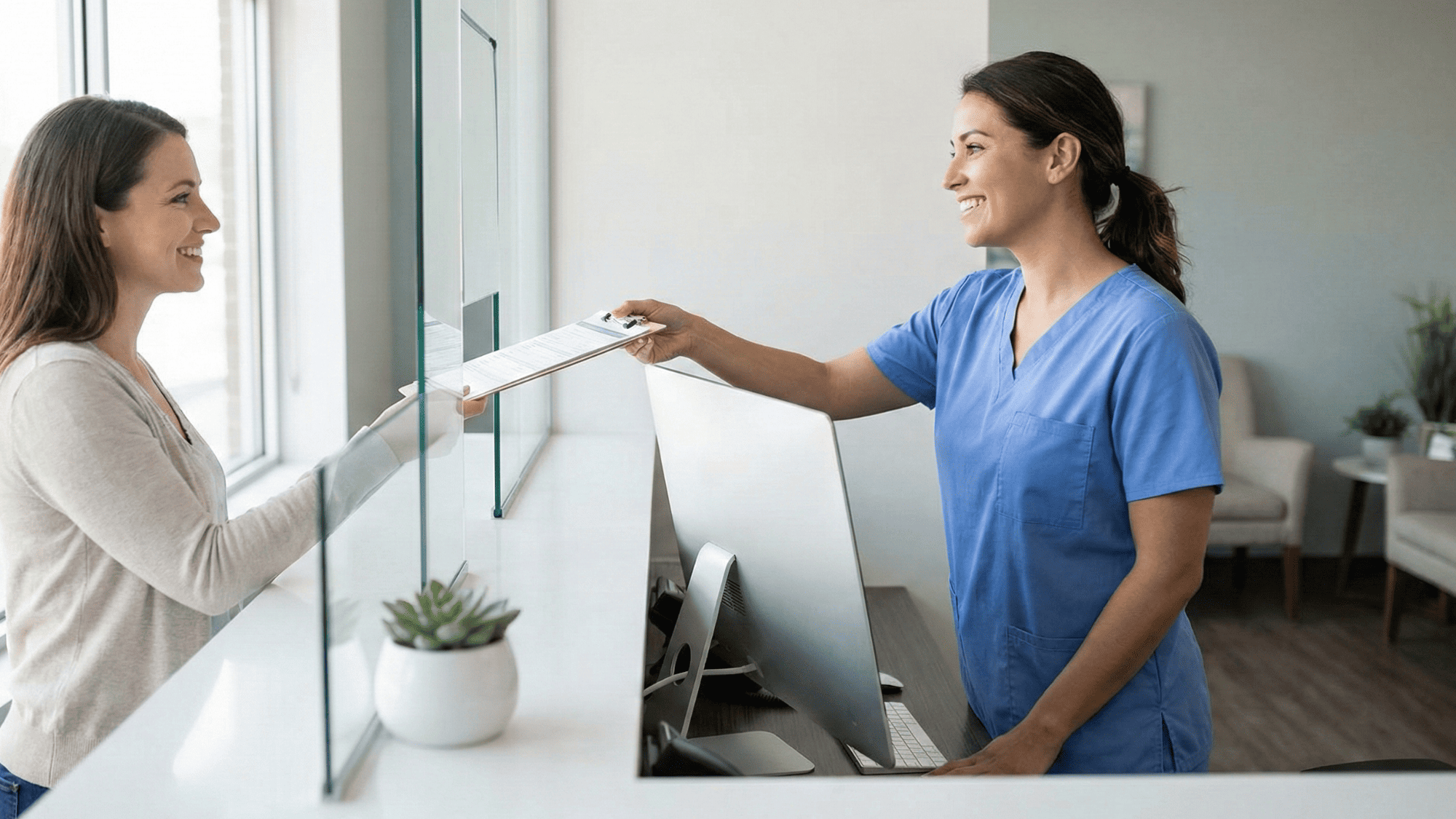 Smiling medical receptionist handing a clipboard to a patient at a clean organized front desk