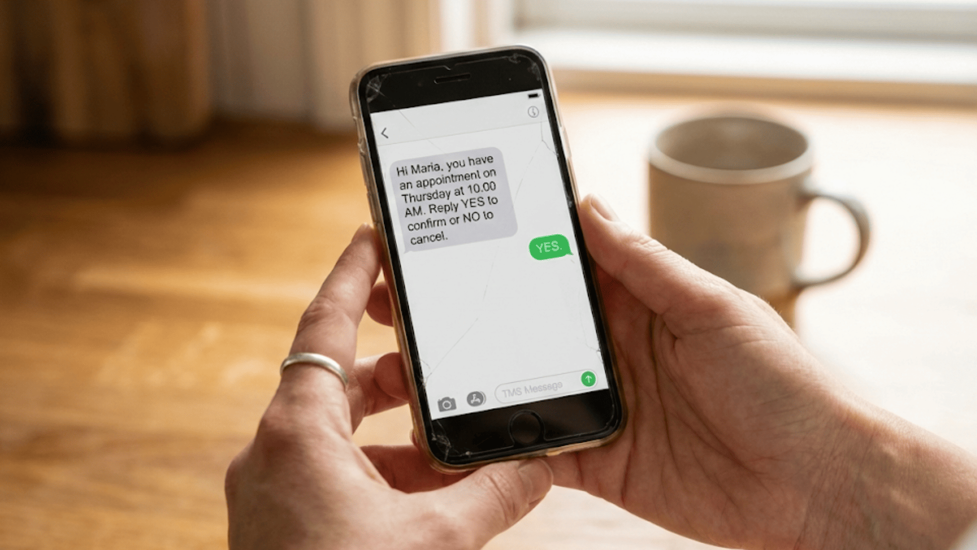 Patient holding phone confirming a medical appointment by text message with a simple YES reply