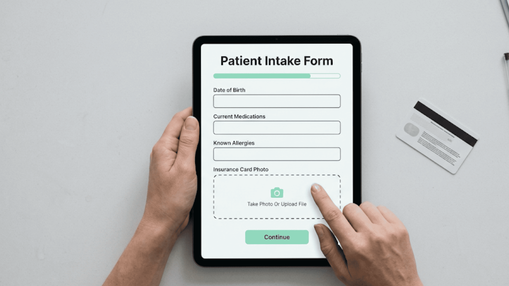 Overhead view of a patient completing a digital intake form on a clinic tablet, tapping the insurance card photo upload field