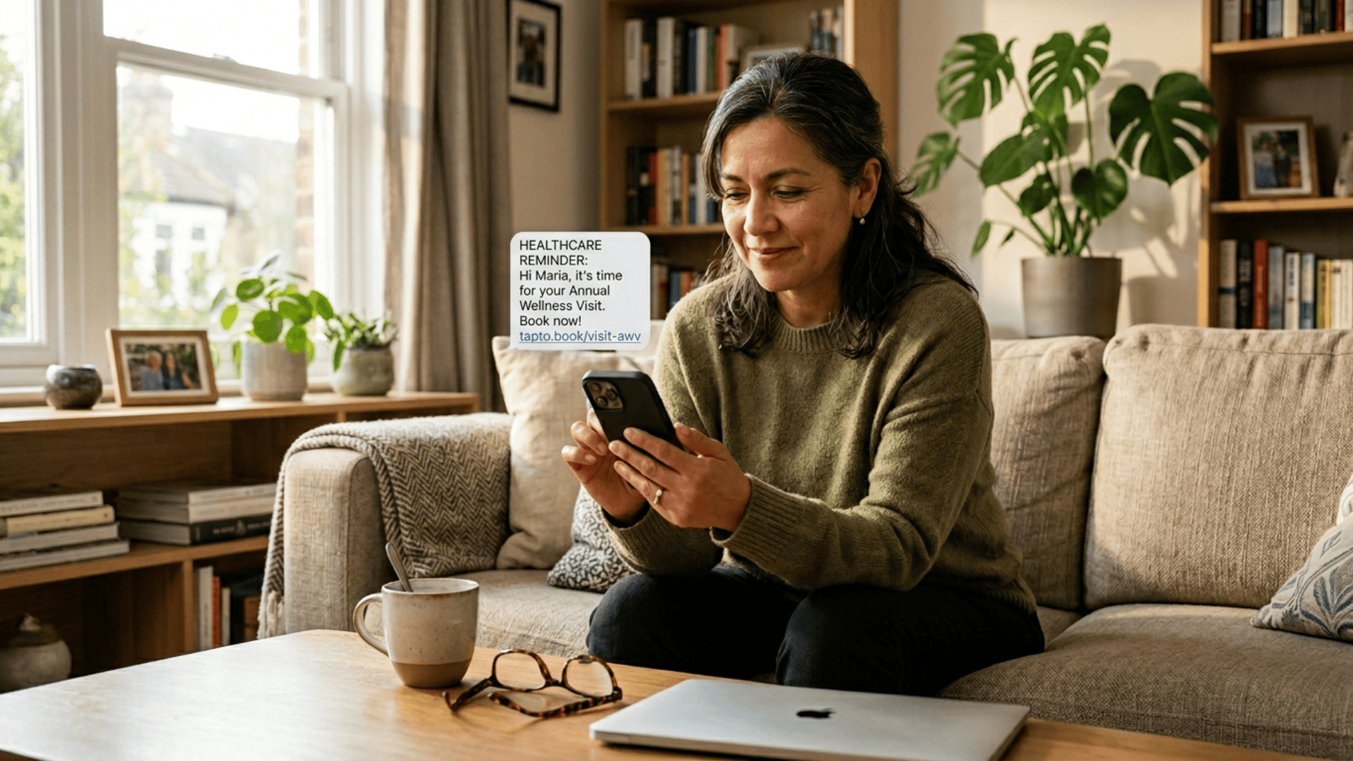 Patient at home reading a text reminder to book her annual wellness visit on her smartphone.