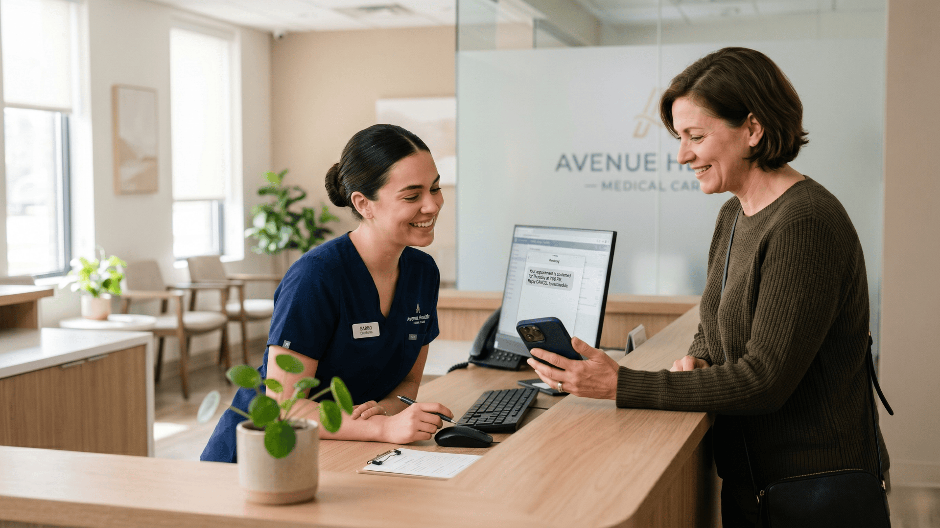 Patient showing SMS appointment confirmation to clinic receptionist at front desk