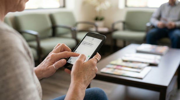 Over-the-shoulder view of an elderly patient texting on their phone in a clinic waiting room