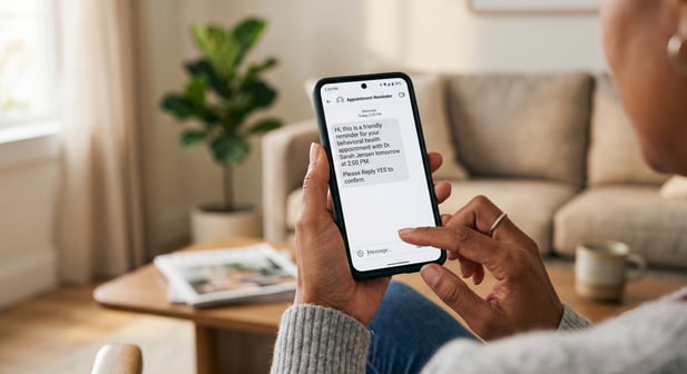Close-up of a patient holding a smartphone displaying an appointment reminder text message