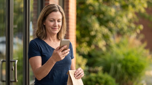 Woman viewing a review request text on her phone outside a clinic entrance