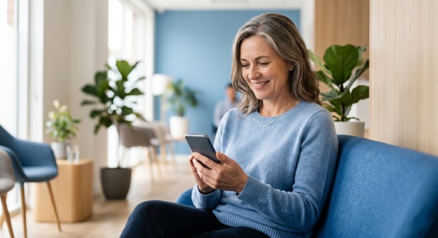 Patient smiling while using smartphone in a modern clinic waiting area
