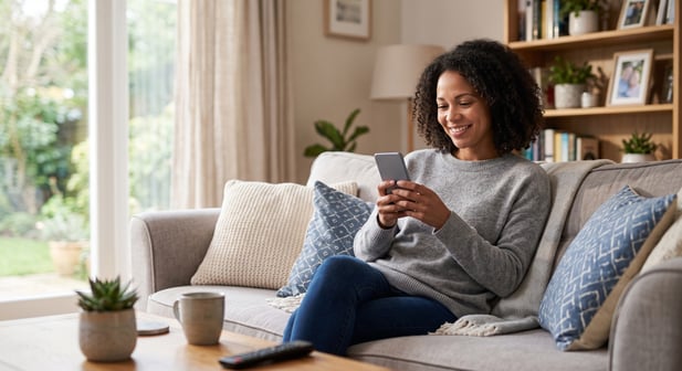 Person using phone conveniently from home couch, demonstrating easy patient payment