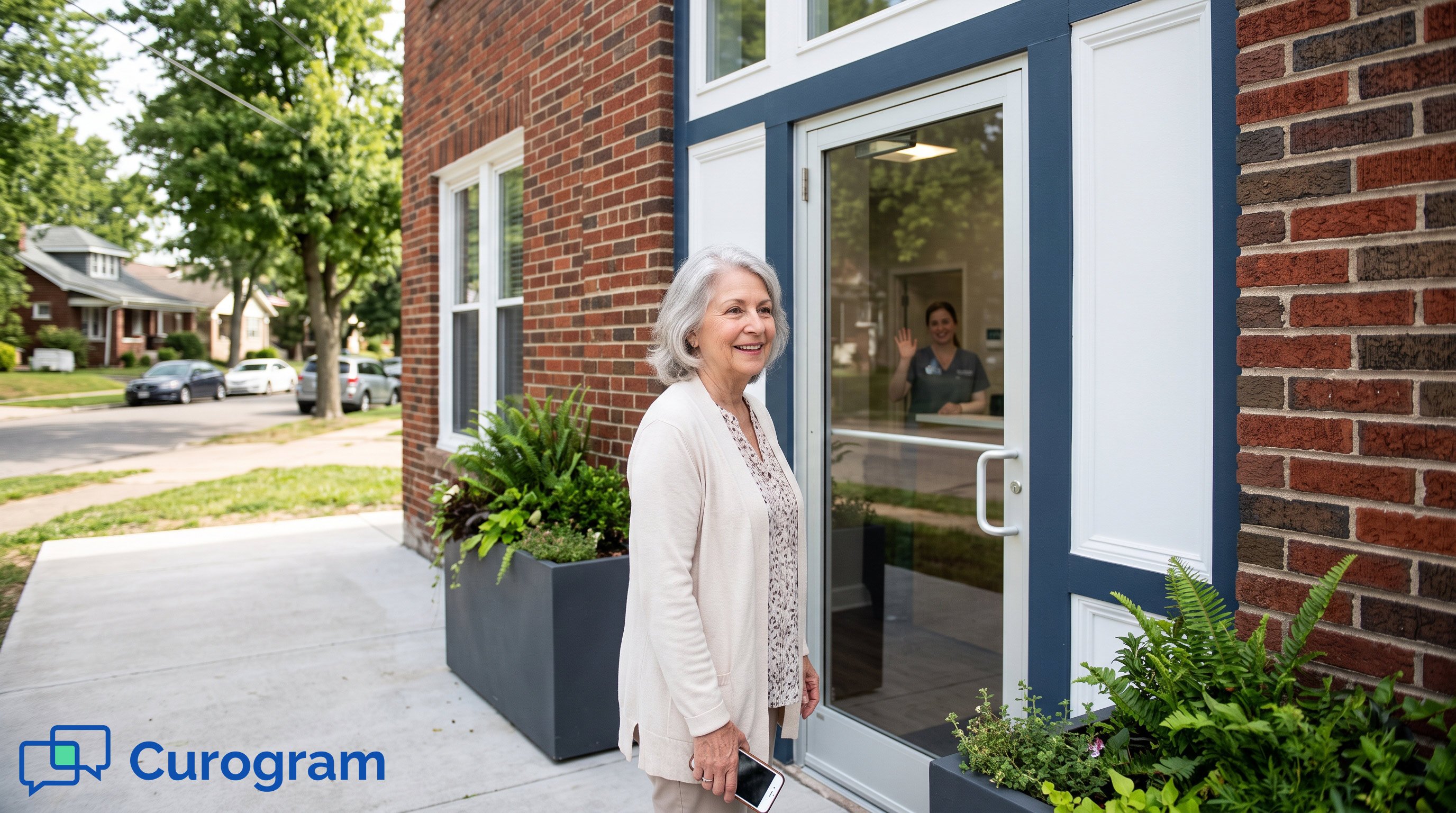 Patient holding phone outside medical clinic as staff waves through glass door