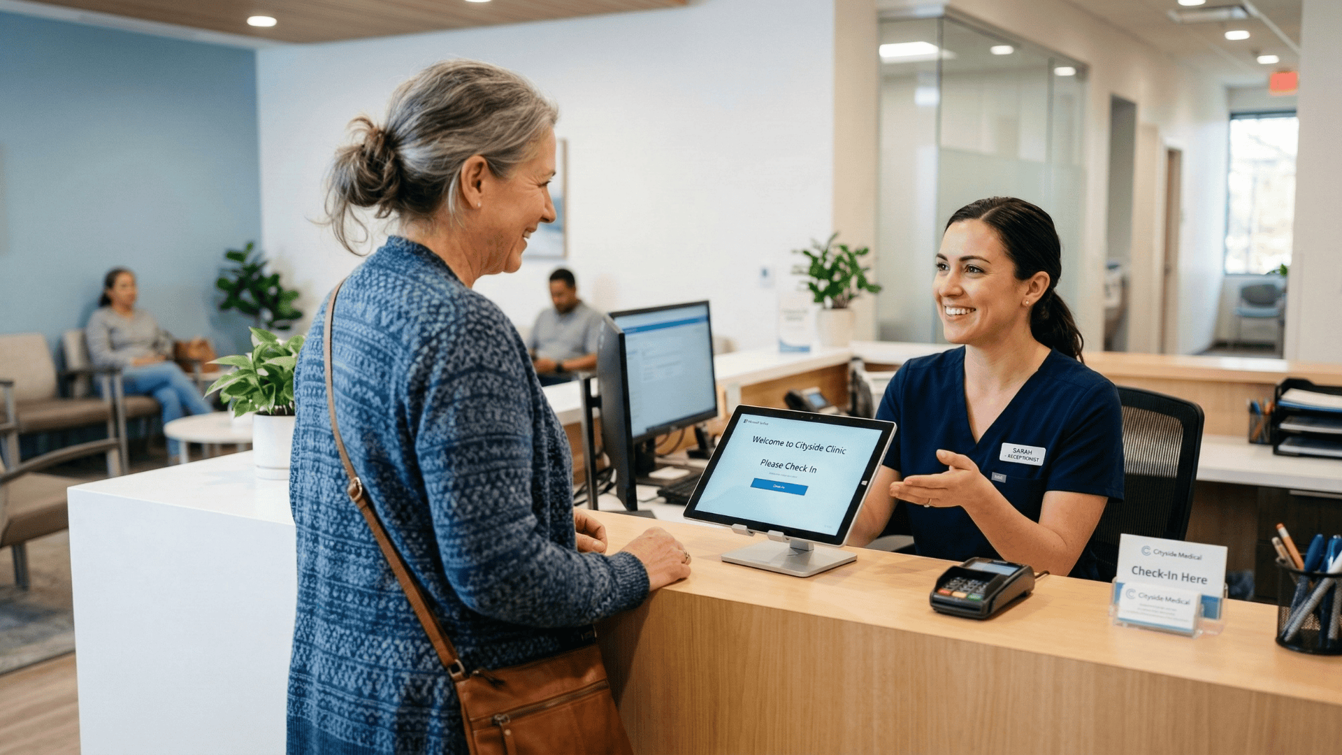 Patient checking in at a medical front desk with a staff member