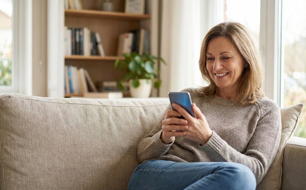 Smiling woman engaged with a digital health message on her phone at home