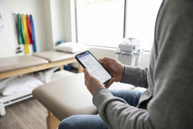Close-up of a patient completing a digital intake form on a smartphone in a physical therapy clinic