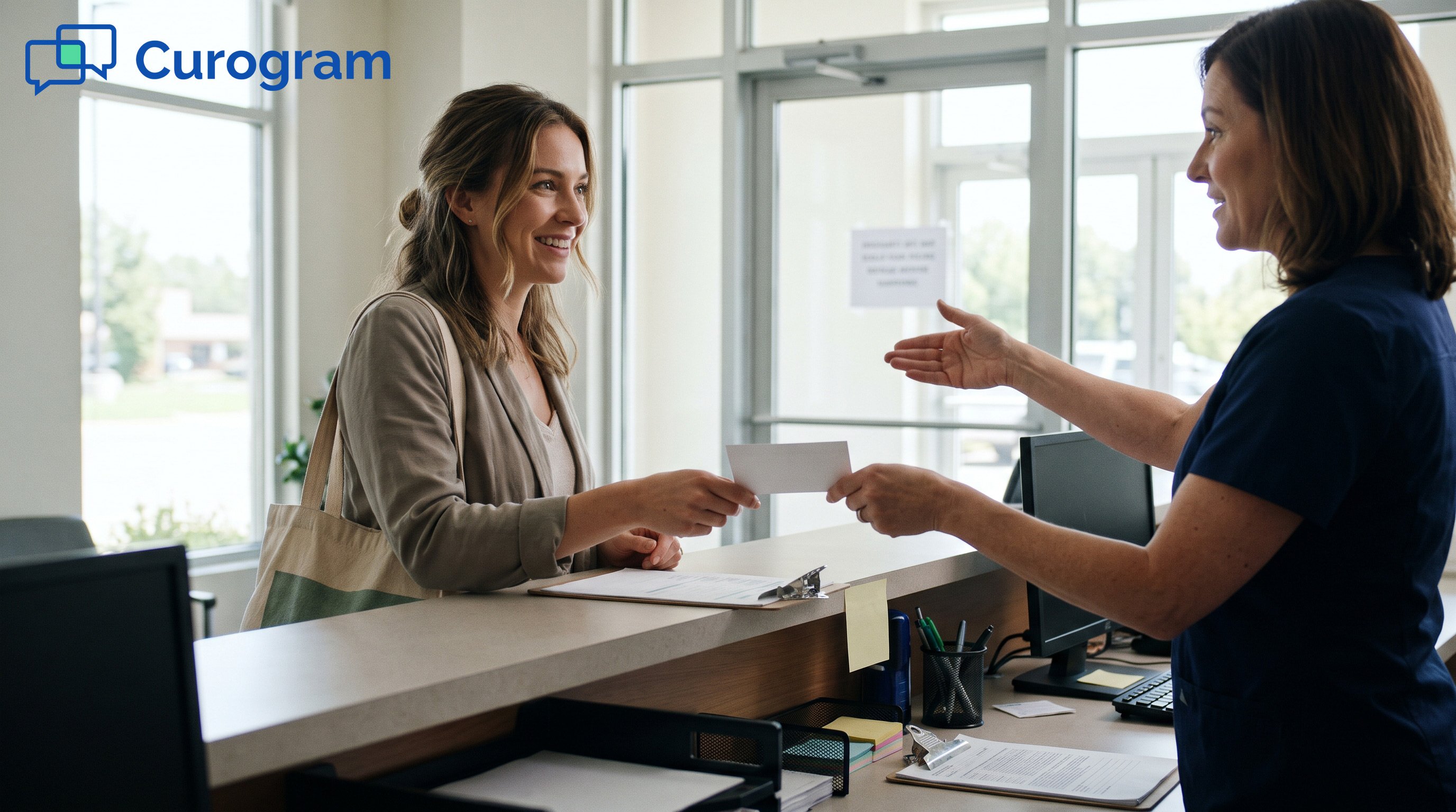 A receptionist hands a patient an appointment card at checkout and points to a sign
