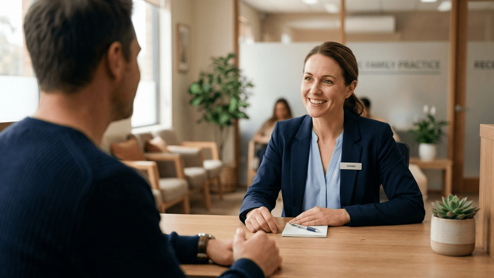 Patient speaking with a medical receptionist at a clinic front desk