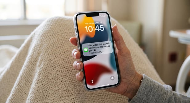 A person holds a smartphone showing a "Telehealth visit starting" notification and video call