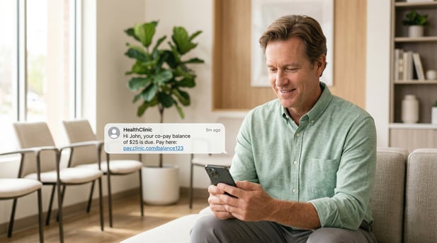 Patient in a waiting room smiles as he receives a mobile text message for a $25 co-pay balance