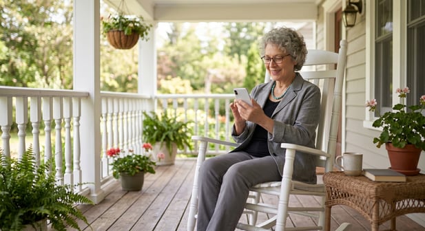 An older woman sitting on a porch looking at a smartphone