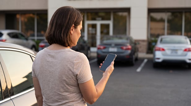 Patient checking an appointment text reminder on a smartphone in a clinic parking lot