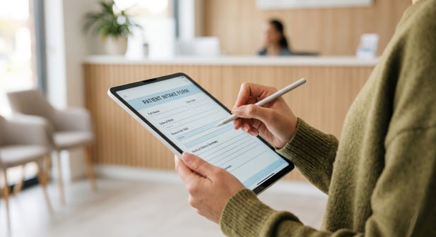Close-up of patient hand using stylus on tablet for digital intake form in medical office