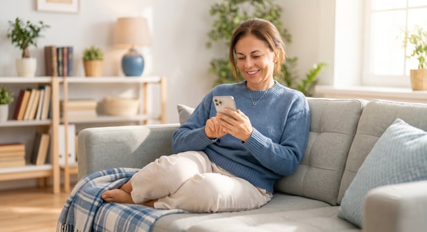 Relaxed patient using a smartphone on a couch, illustrating digital ease