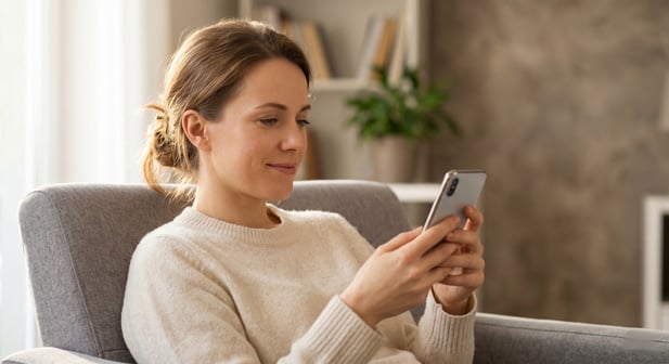A medical biller sits at a desk, looking relieved as a patient pays easily on their phone